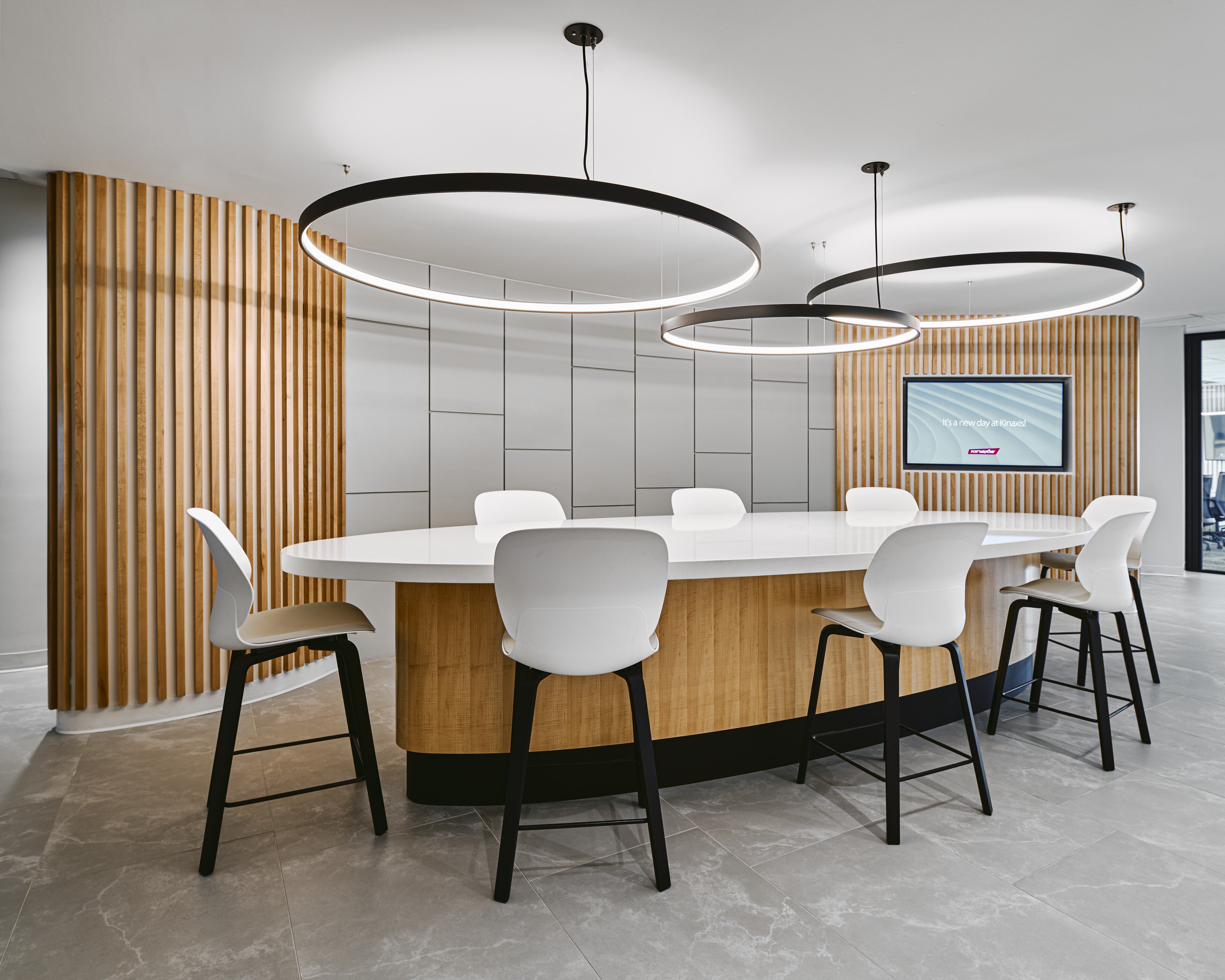 Café counter at Kinaxis headquarters lit by three suspended Delta Light Superloop rings above a white oval counter
