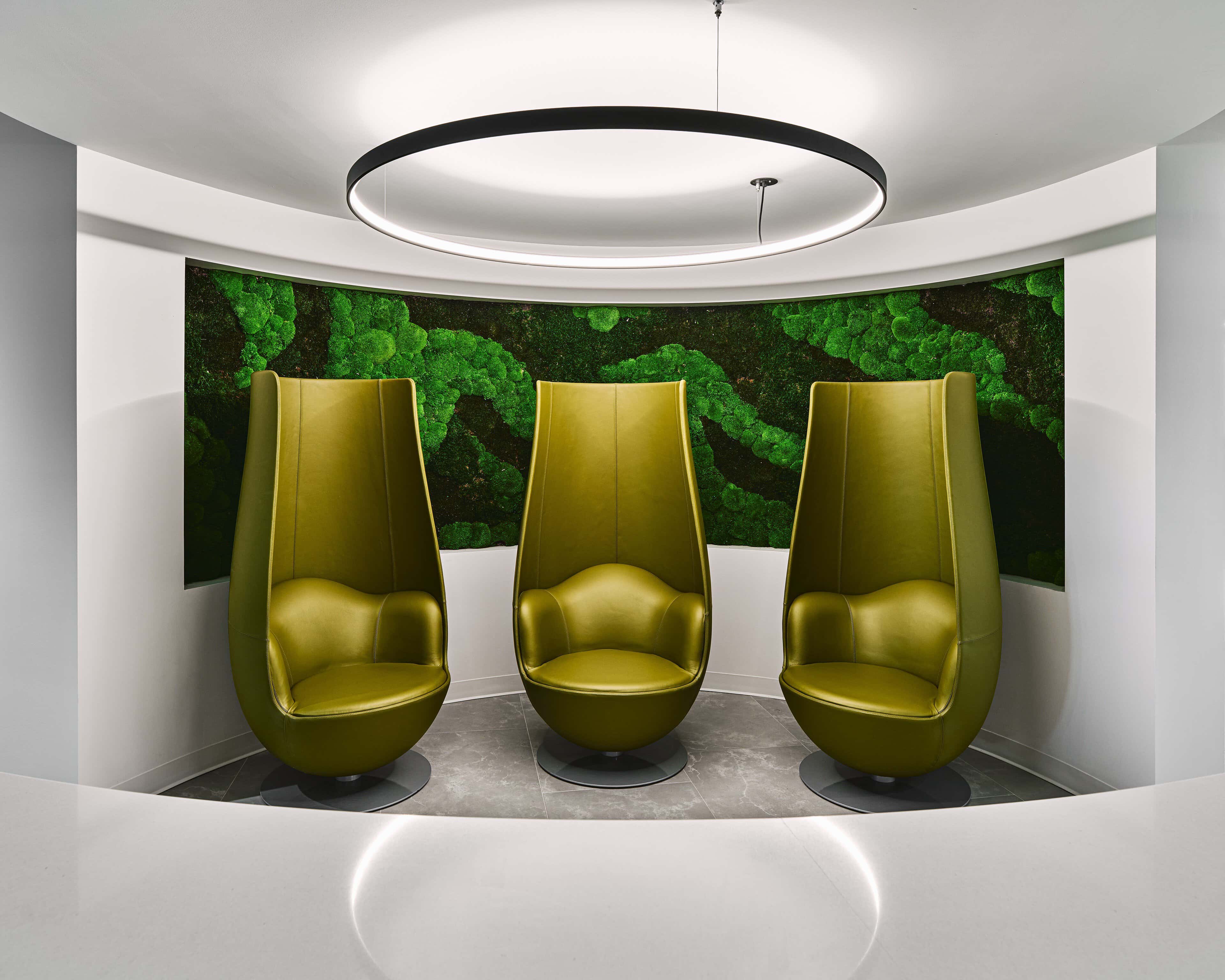Quiet focus nook at Kinaxis with a single Delta Light Superloop ring above high-backed chairs set against a preserved moss wall