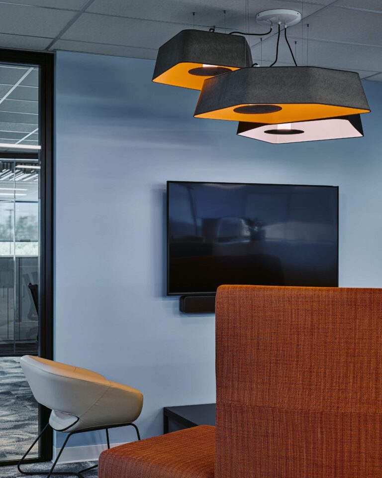 Meeting room at Kinaxis headquarters with large hexagonal felt acoustic pendants in black and amber above soft seating