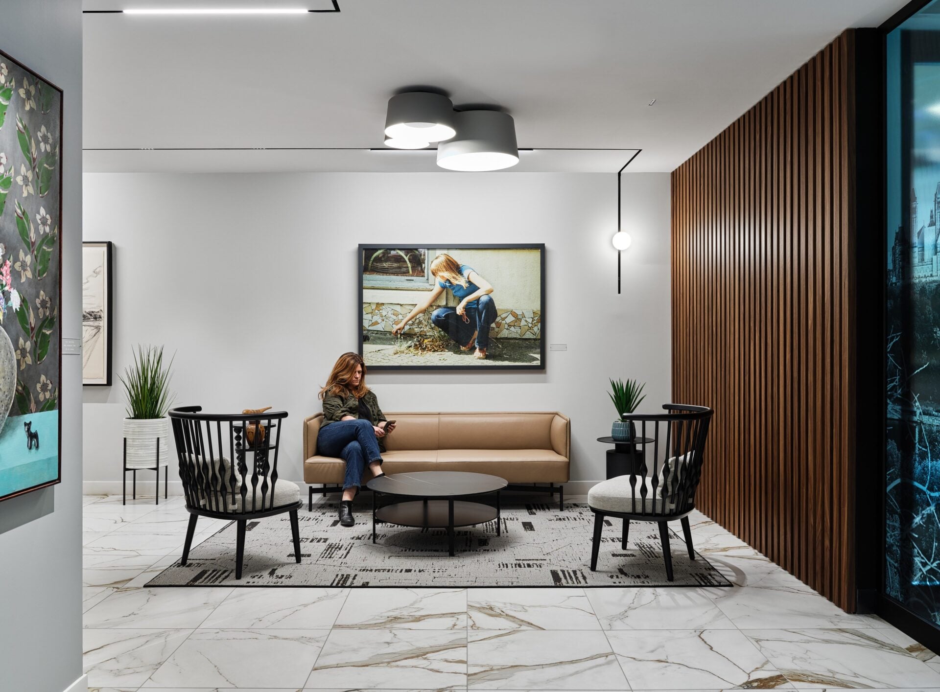 A reception lounge at Osler in Ottawa with a cluster of sculptural felt Luciole Fiona pendants above the seating and accent light on the artwork.