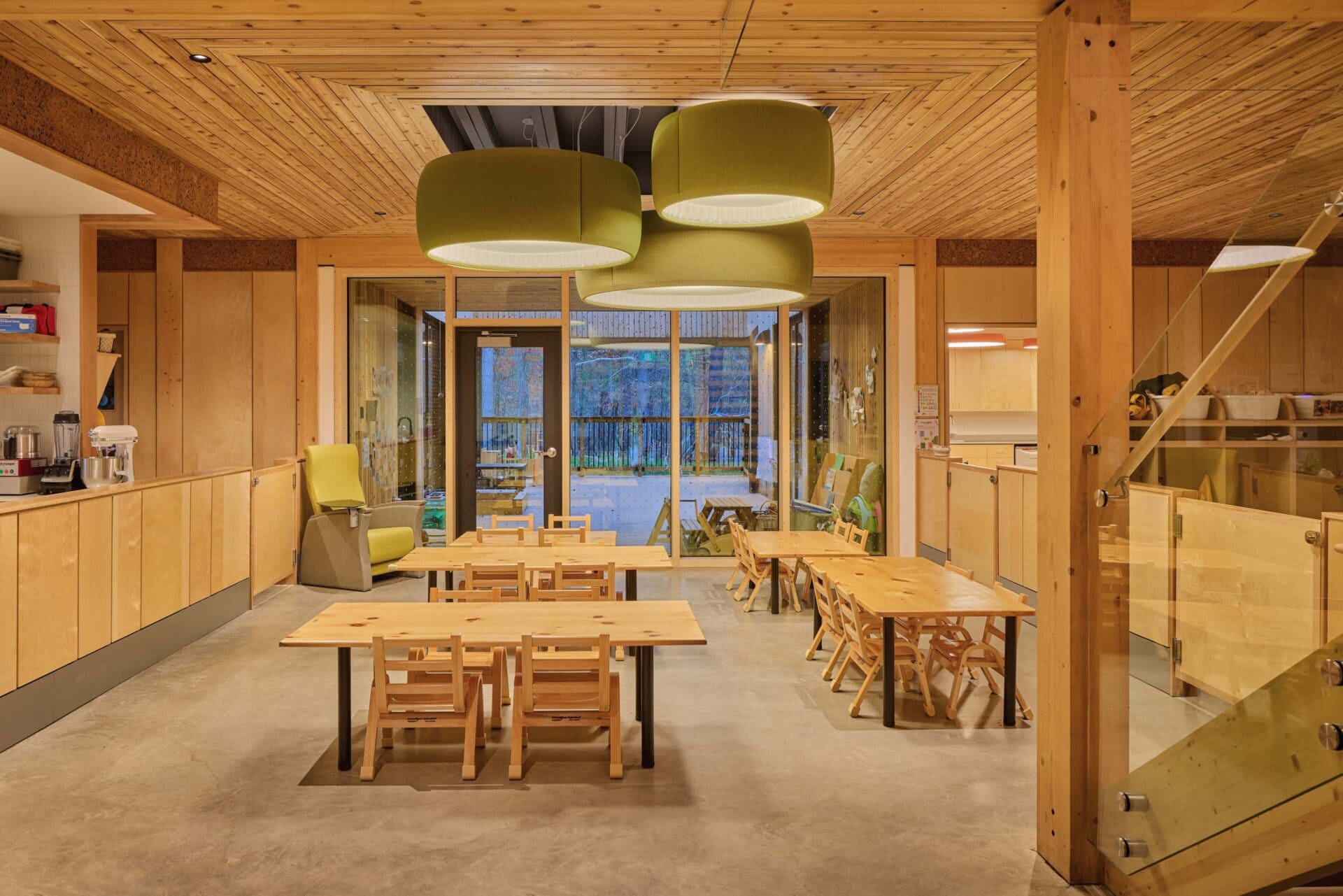 Large fabric-covered acoustic drum pendants over the communal dining tables at Forest and Nature School, Ottawa