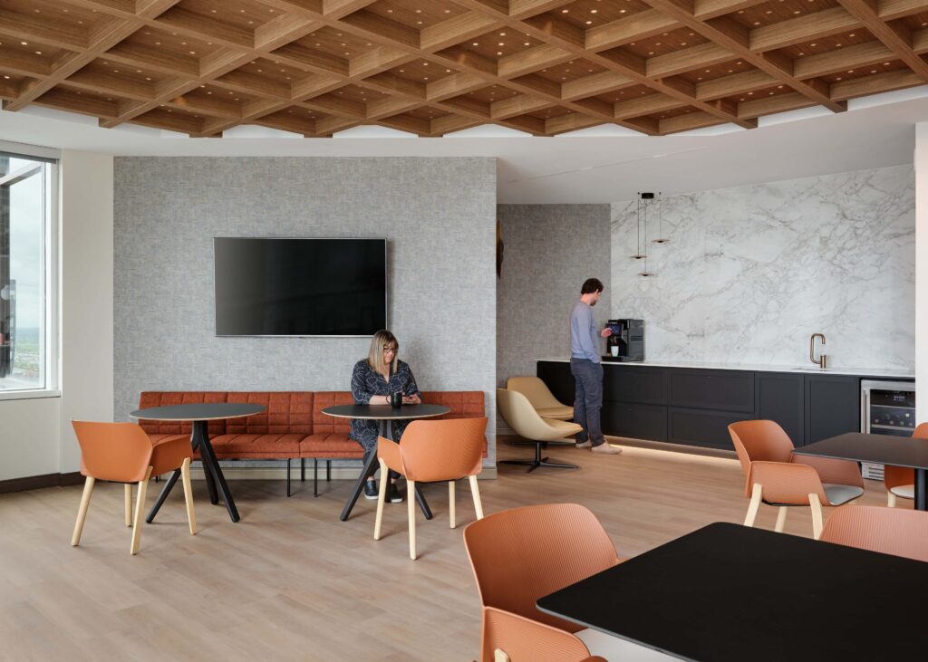 Breakout lounge under the timber waffle ceiling and marble media wall at Smart & Biggar Montréal