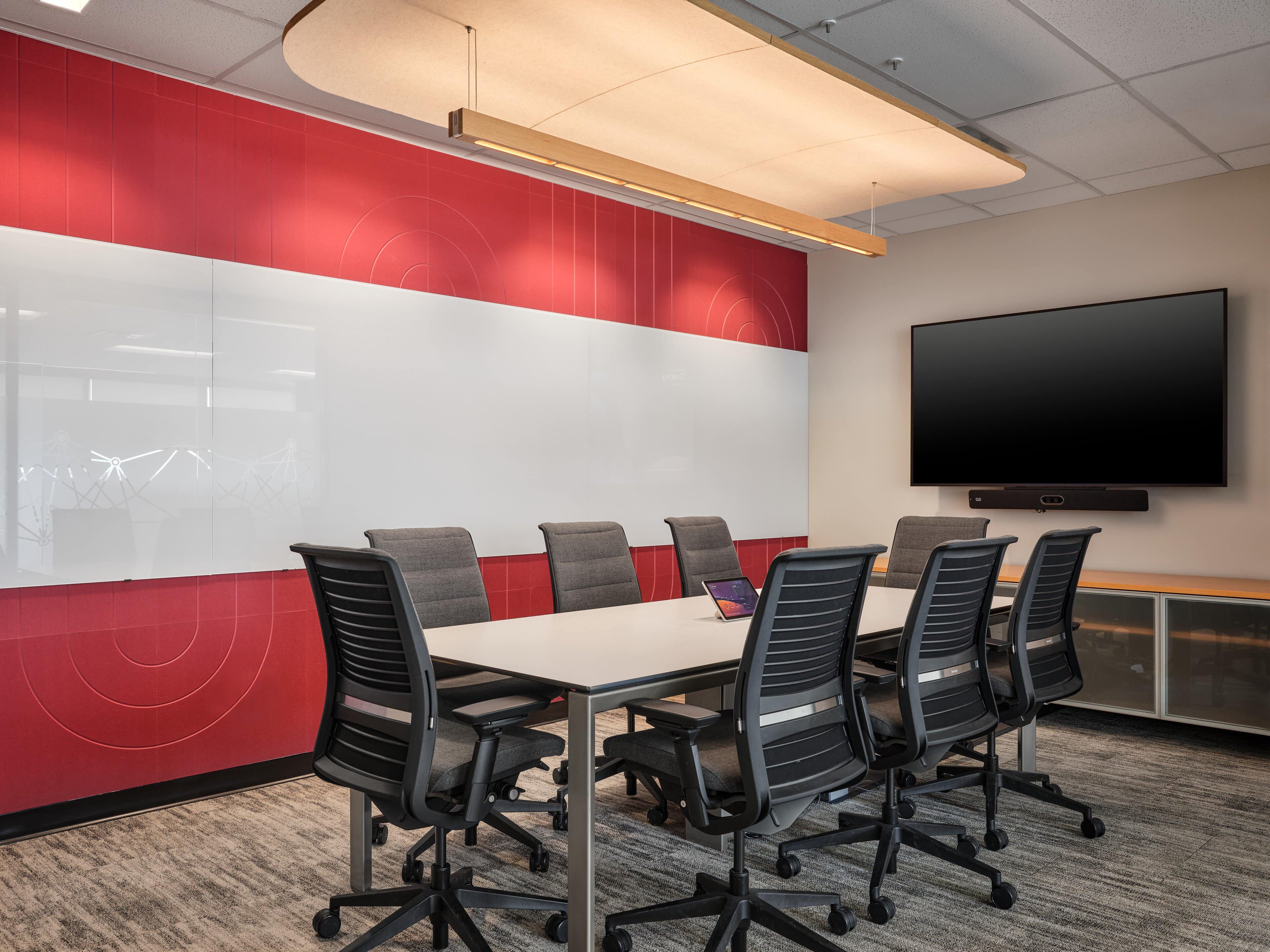 Aaline suspended acoustic luminaire over the CIRA boardroom table with a red concentric feature wall