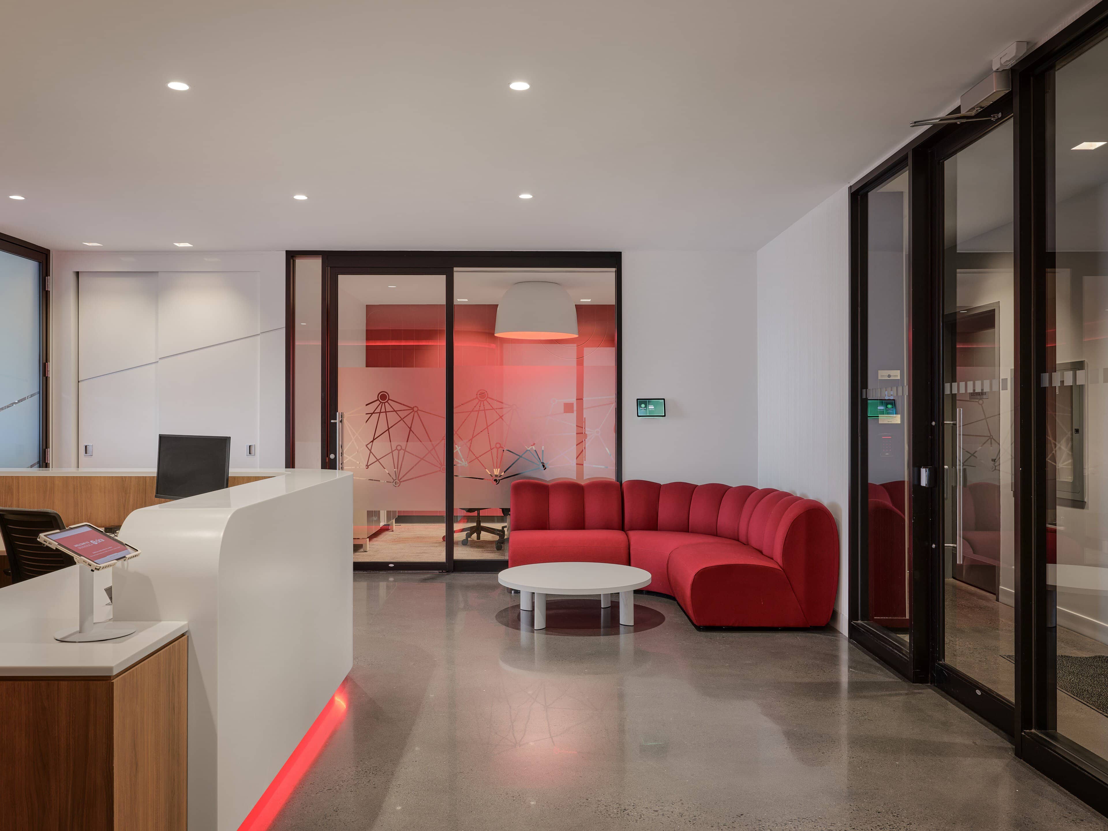 Reception lounge with red banquette seating beyond the desk at CIRA, Ottawa