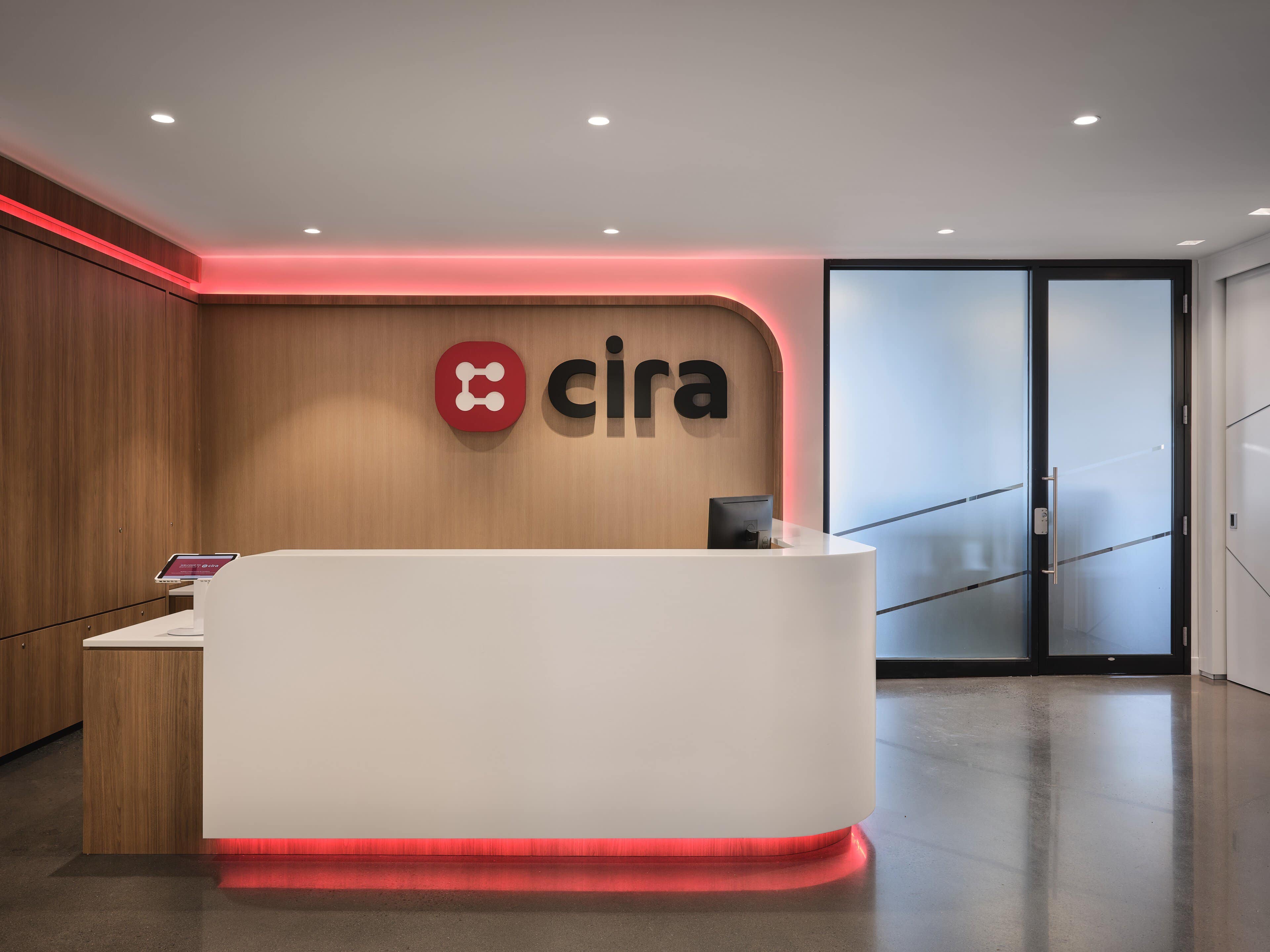 Red RGBW cove light washing the walnut logo wall behind the reception desk at CIRA, Ottawa