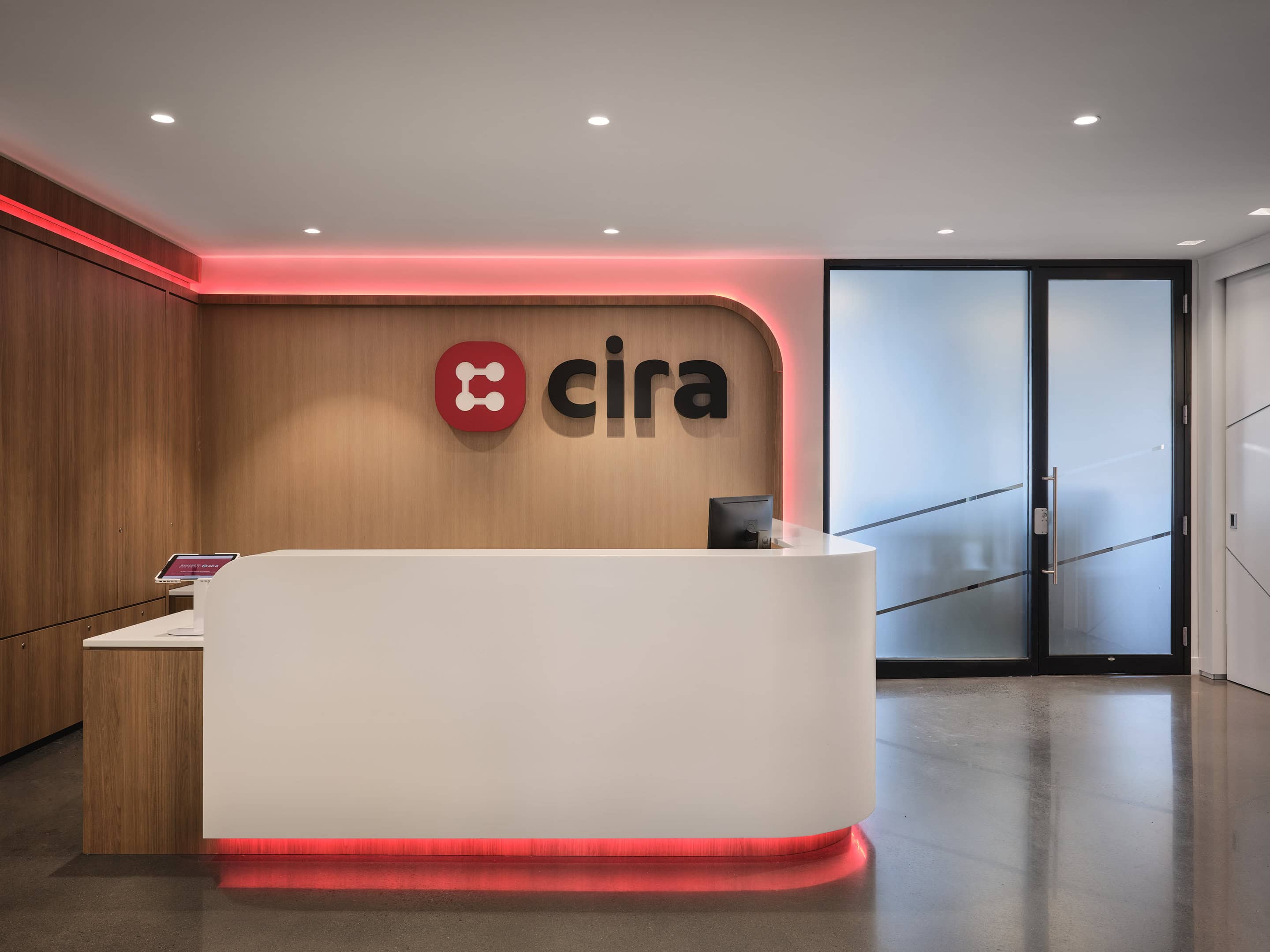 Red RGBW cove light washing the walnut logo wall behind the reception desk at CIRA, Ottawa