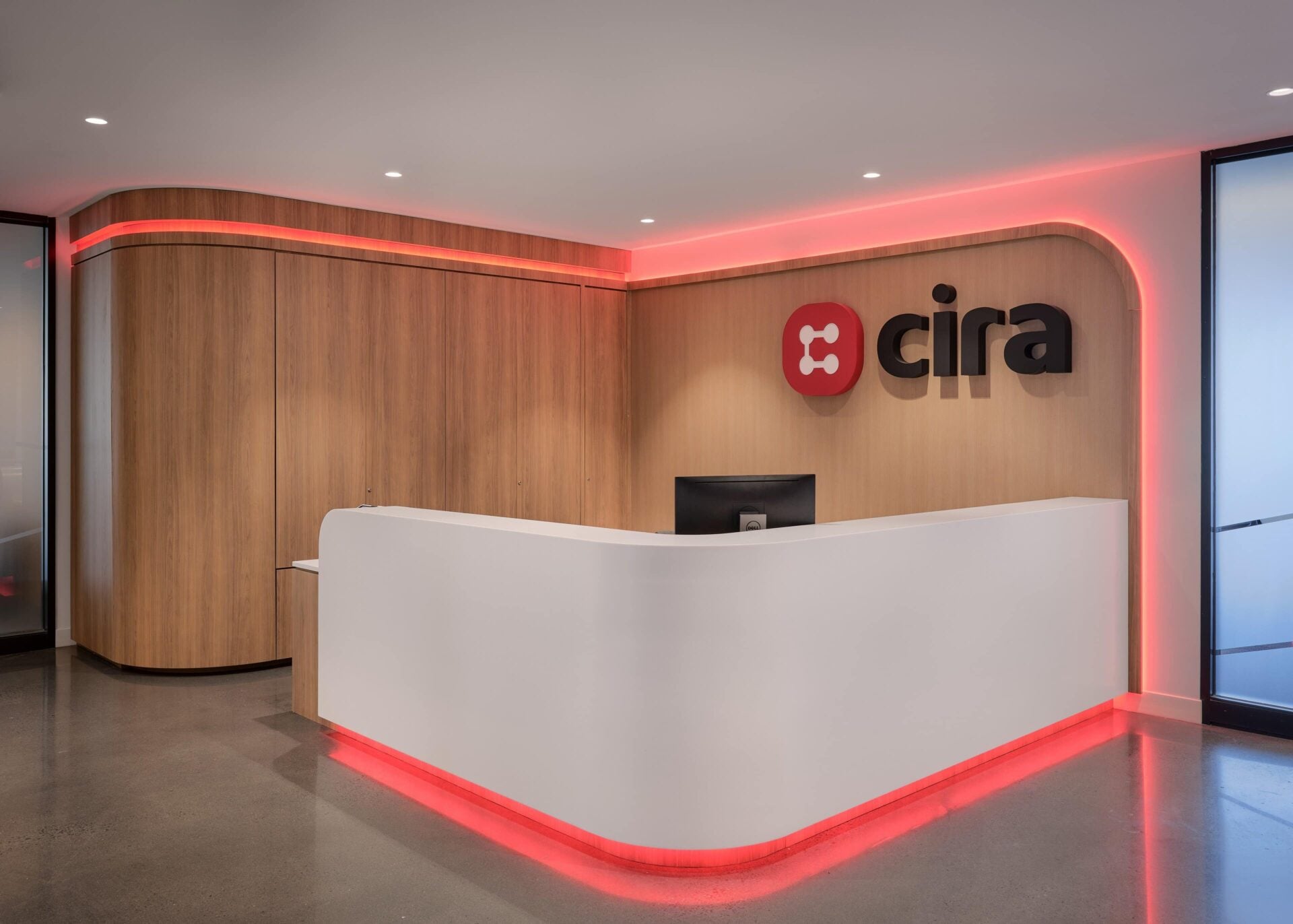 Nova Flex RGBW cove lighting in red, wrapping the curved walnut millwork header and the underside of the reception desk at CIRA, Ottawa