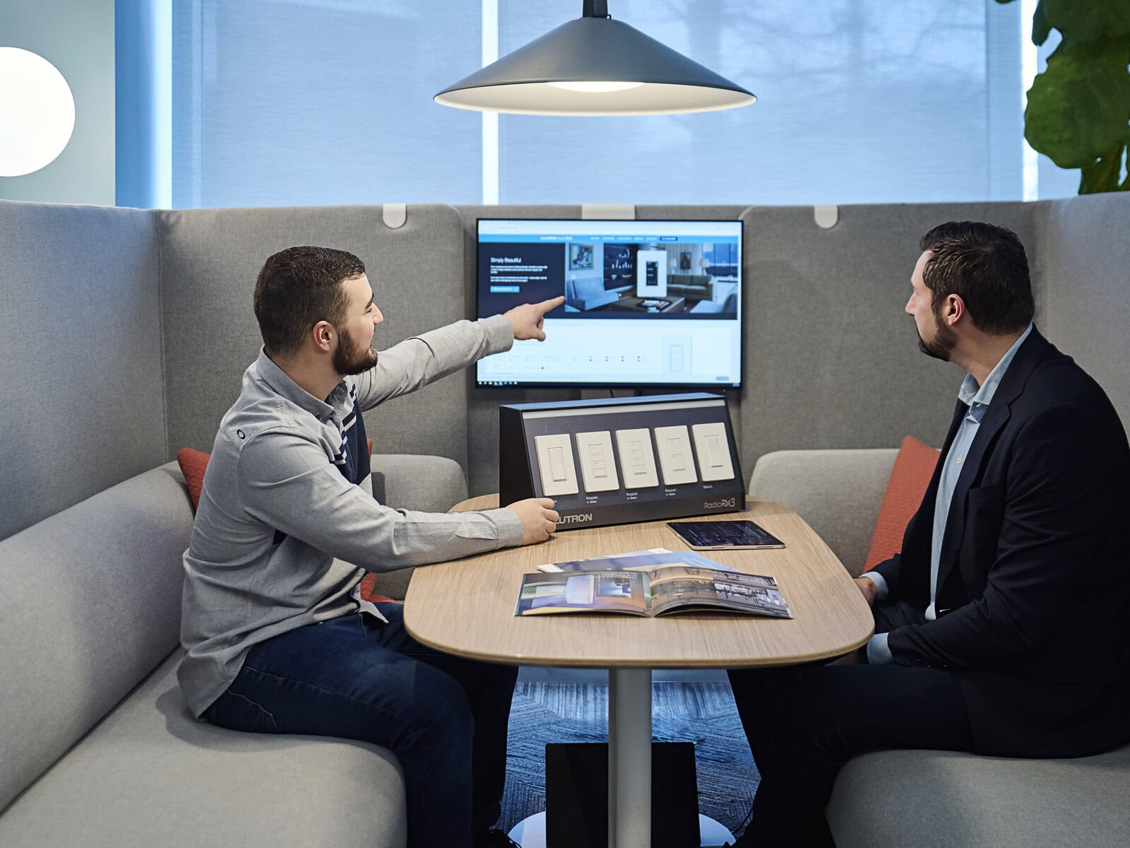 Two people reviewing lighting product information at a screen in an office booth.