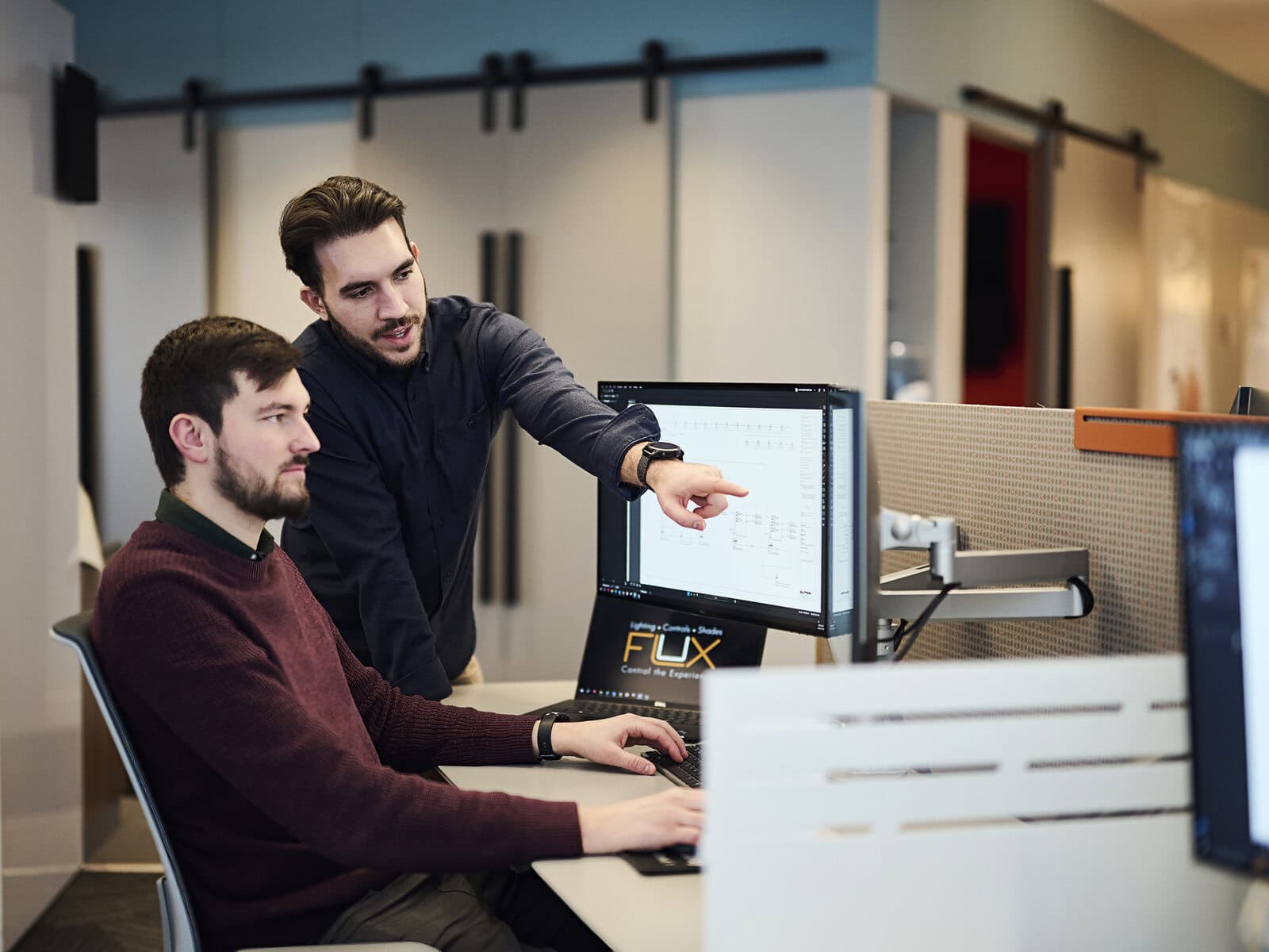Two specialists reviewing lighting calculations on a computer monitor.