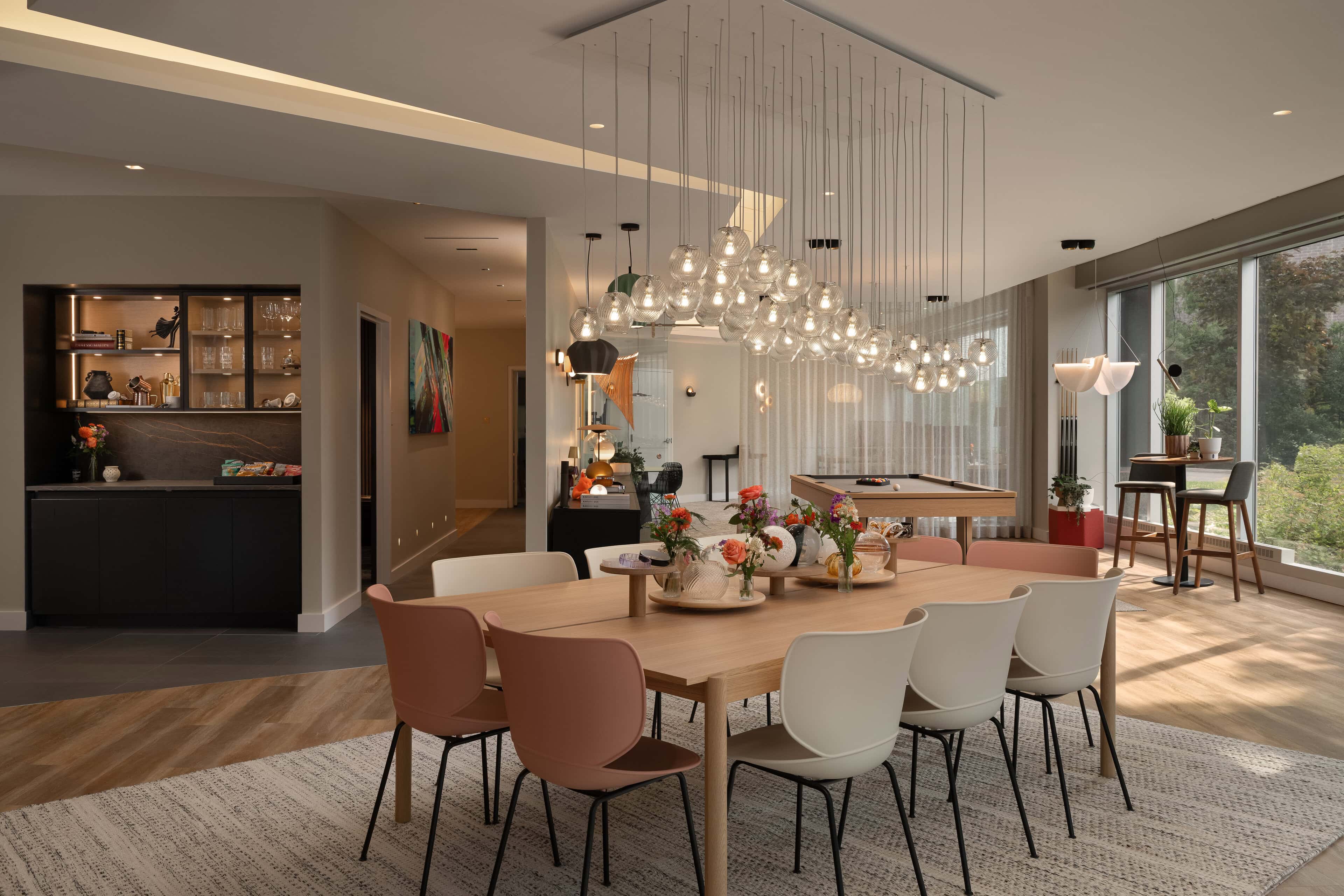 Flux Lighting showroom, Ottawa — the dining table under a linear pendant cluster, with the whole room lit warm.