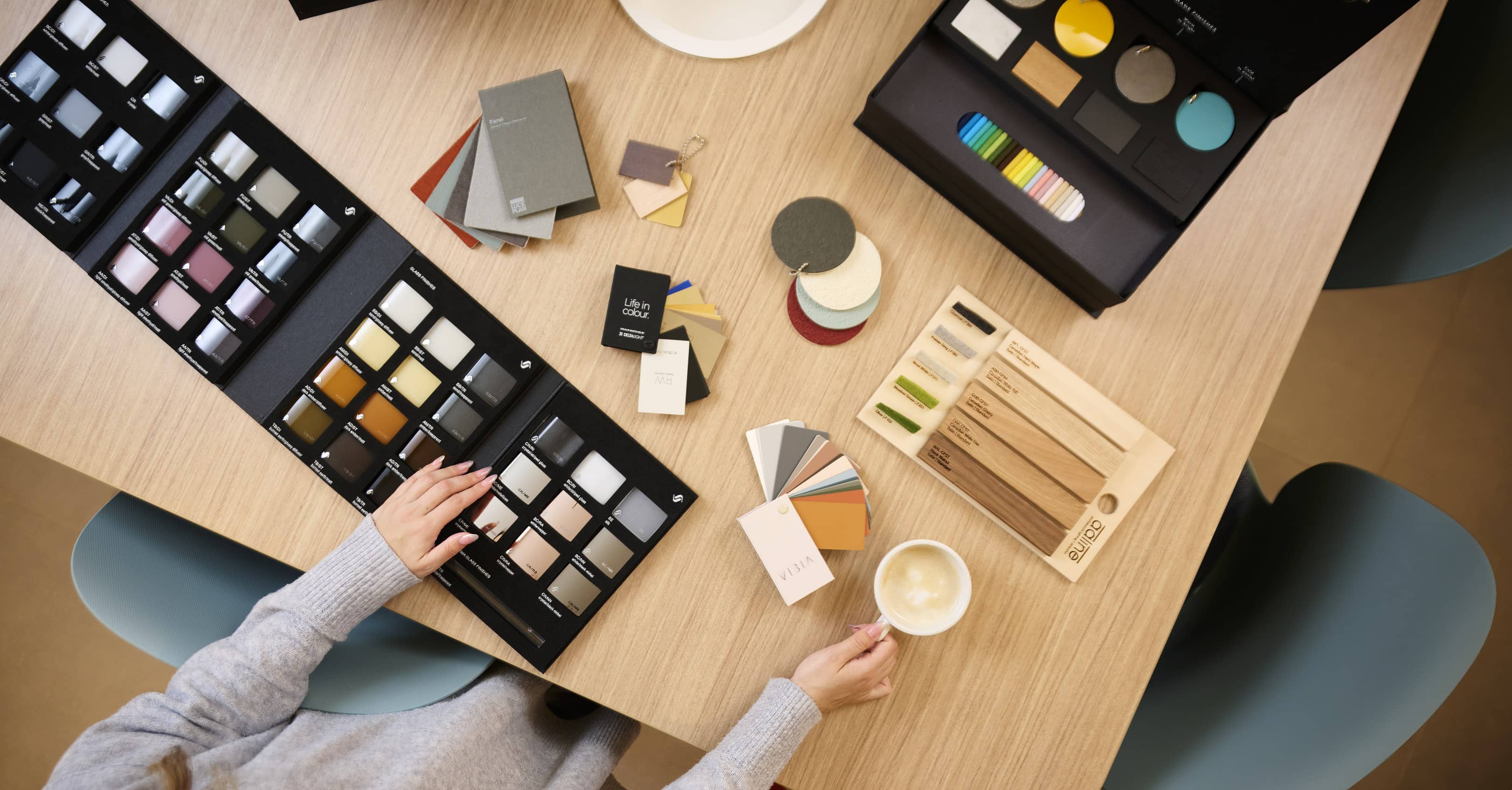 Flux Lighting showroom, Ottawa — finish and colour samples spread across a table, with metal discs, fabric swatches and painted chips under review.