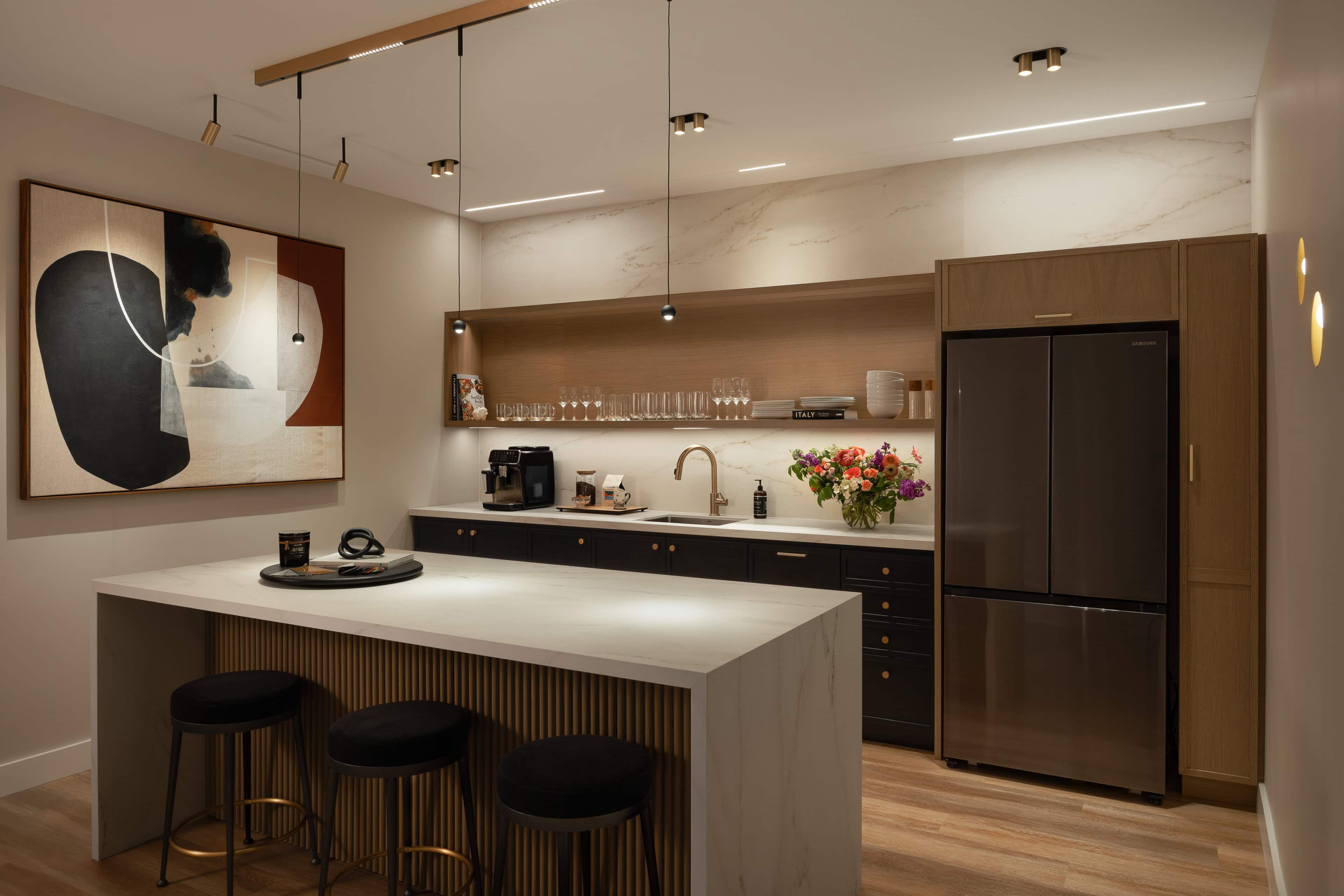 Flux Lighting showroom, Ottawa — a kitchen island with stools under linear pendants and recessed downlights.