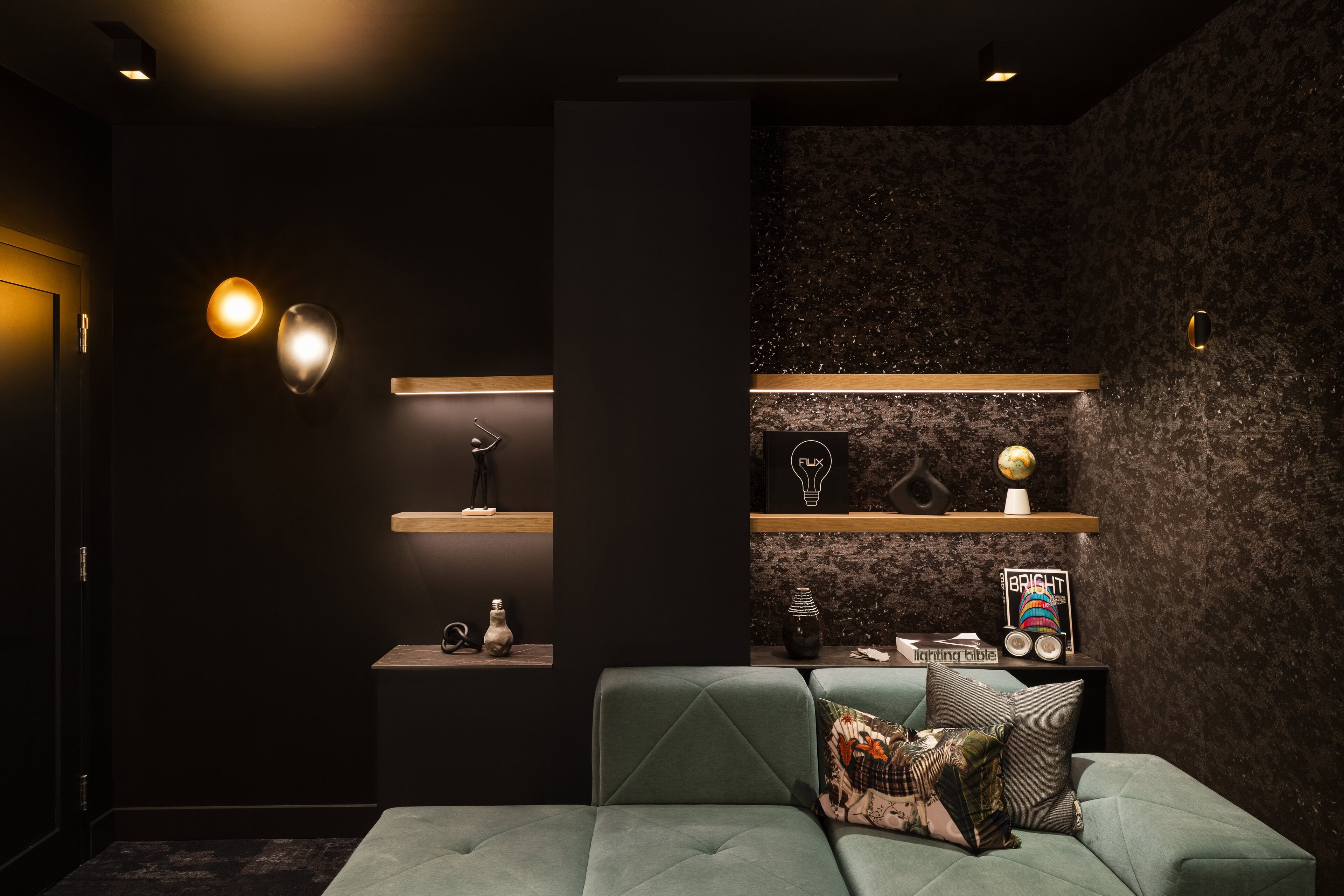Flux Lighting showroom, Ottawa — a dark lounge with lit shelving, wall sconces and a textured feature wall.