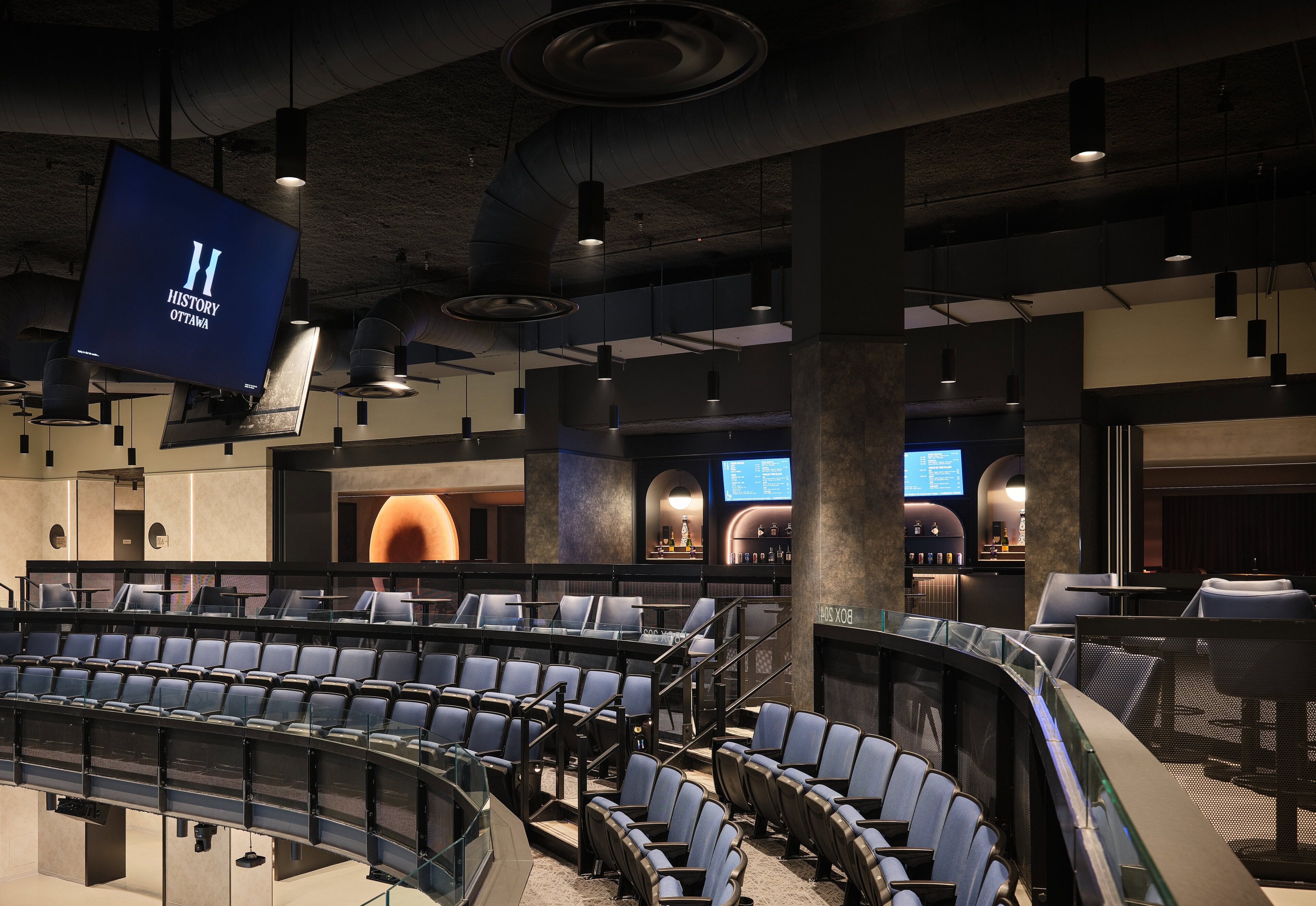 The reserved seating tier on the balcony at HISTORY Ottawa, pendants over the rail and lit arch niches behind
