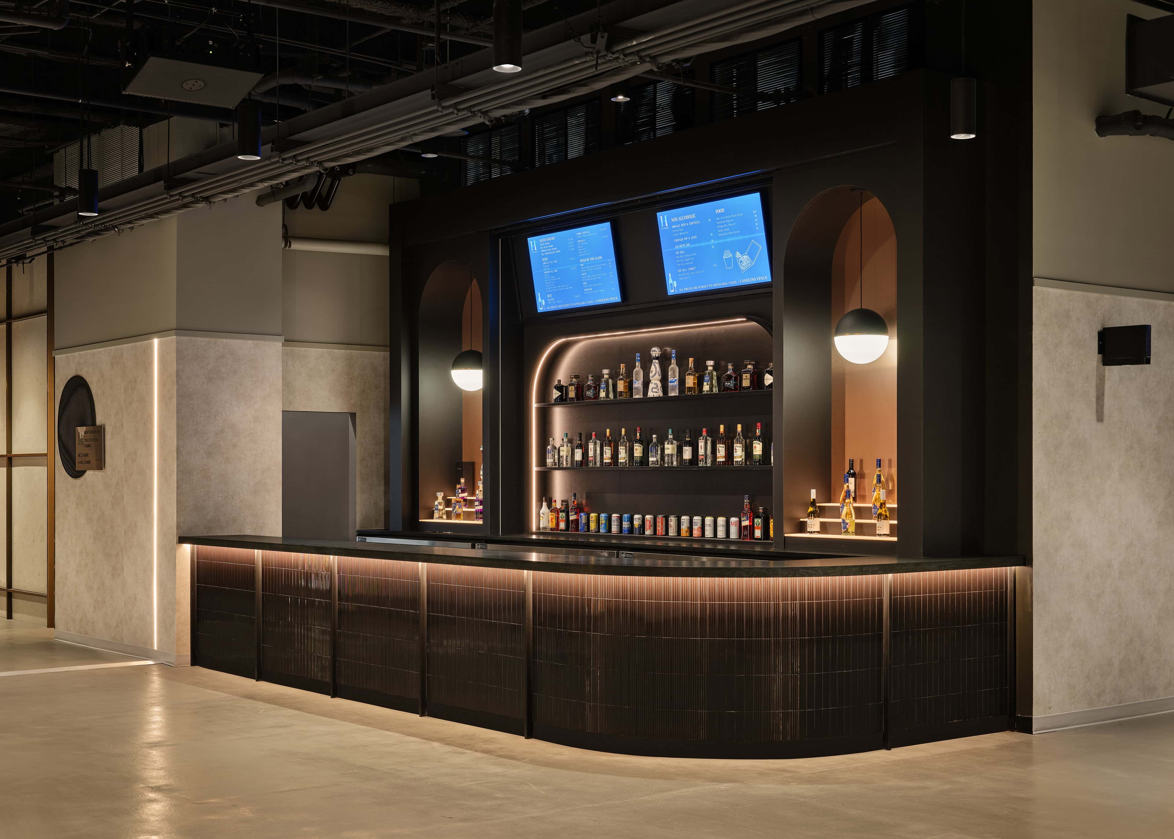 Curved backbar at HISTORY Ottawa with illuminated bottle shelving and a continuous glow under the bar front