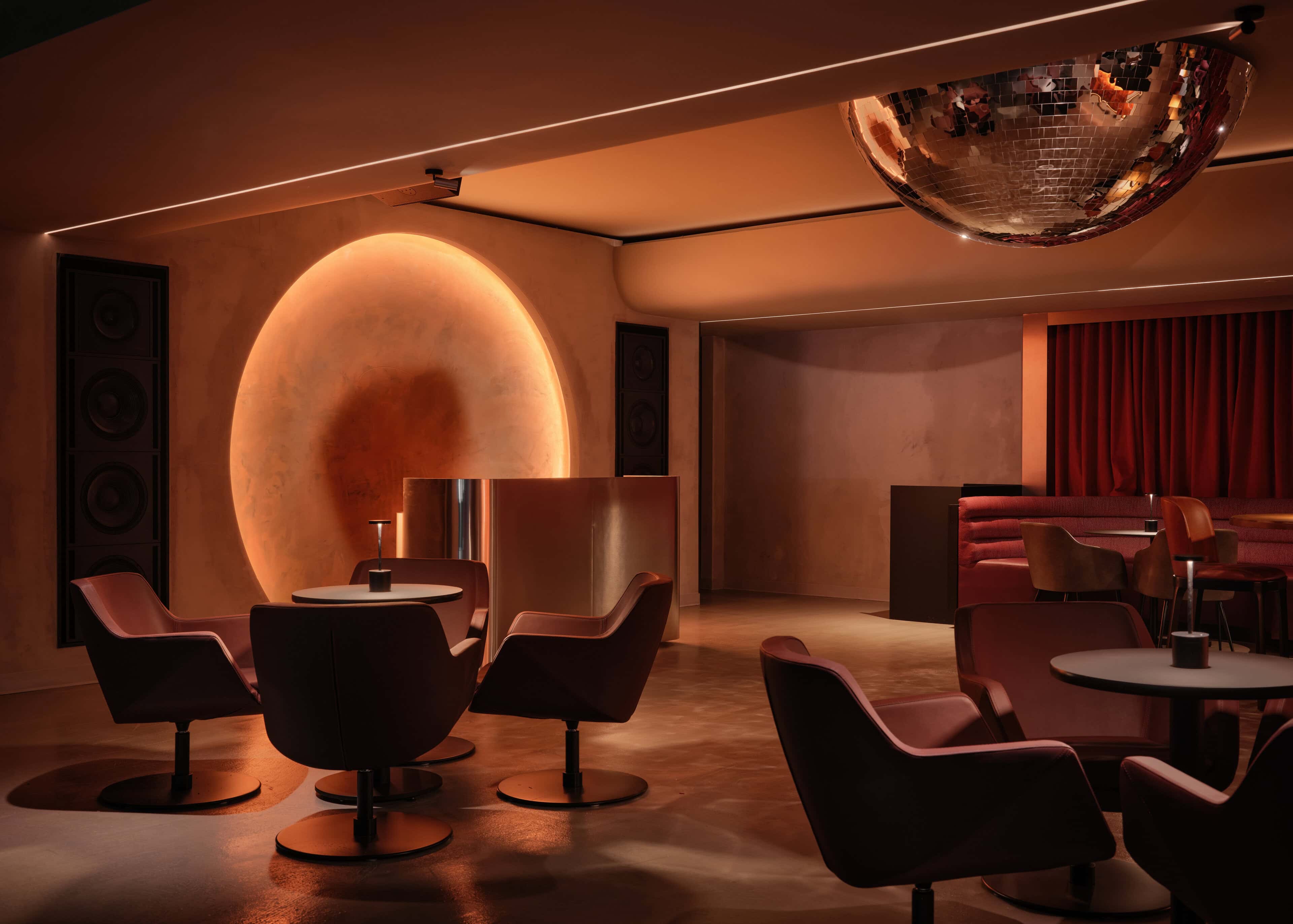 The moon in the VIP lounge at HISTORY Ottawa, a pale disc set into the wall and side-lit from behind its rim, with a half mirror ball on the ceiling above