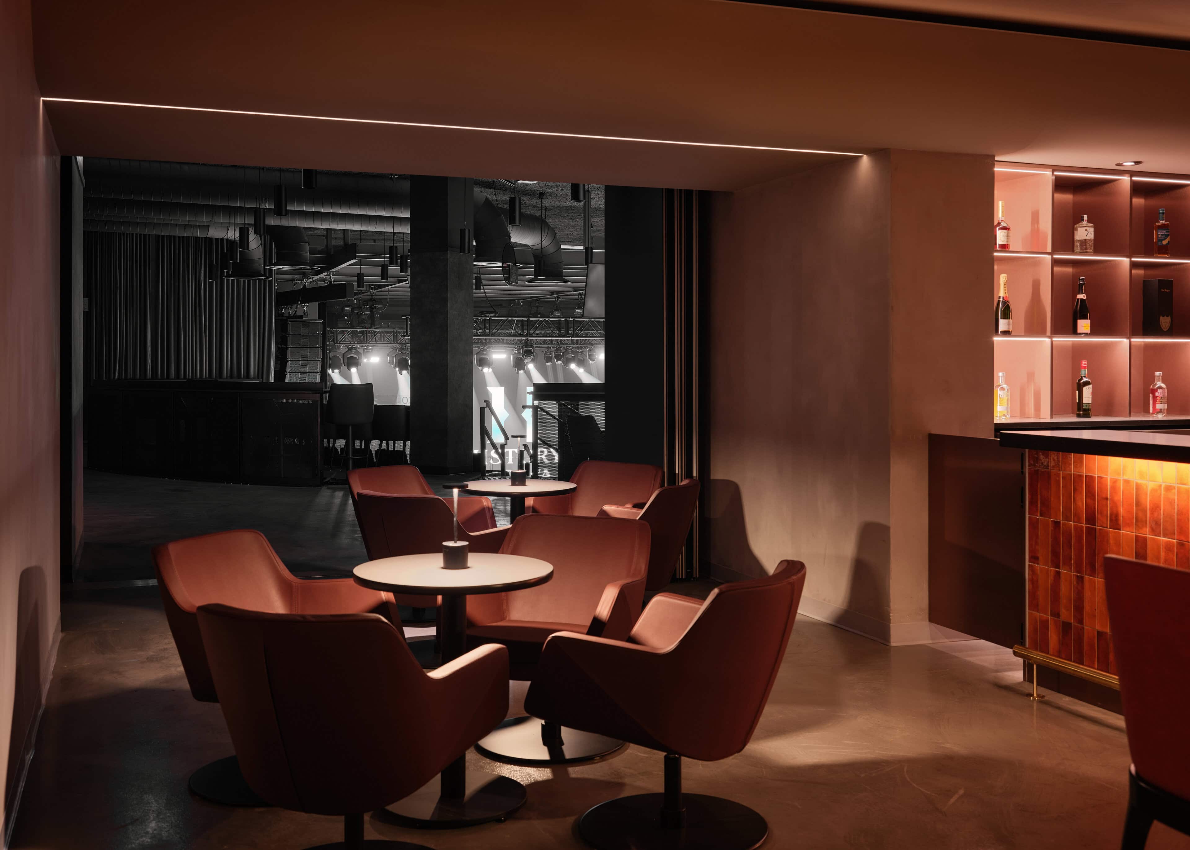 Lounge seating at HISTORY Ottawa looking through to the bar, with warm illuminated shelving beyond