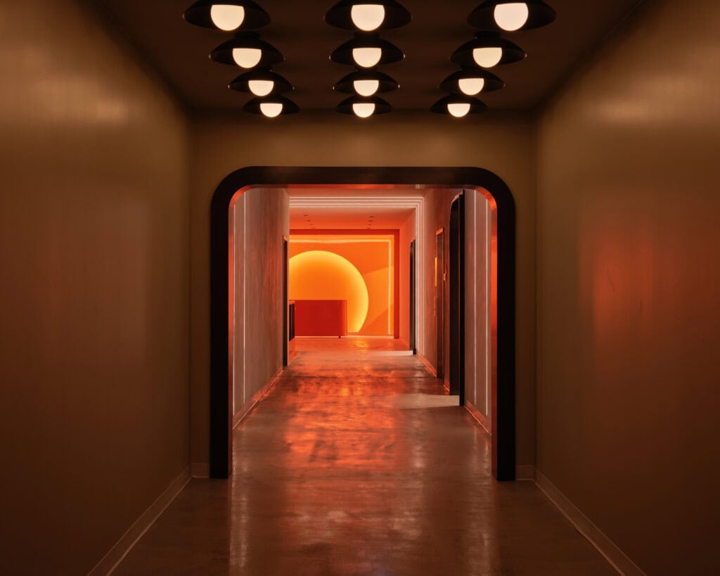 A corridor at HISTORY Ottawa with a cluster of ceiling-mounted globes overhead and a glowing arch at the far end