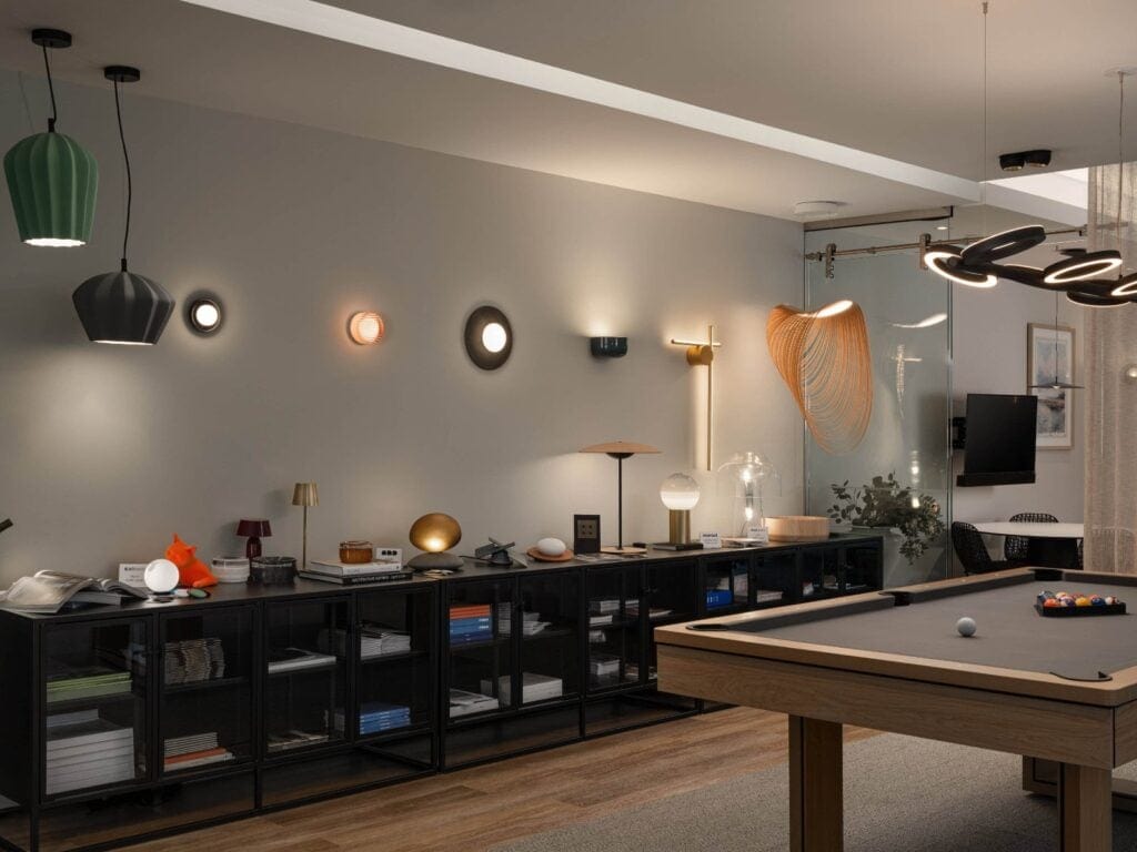 A wall of lit pendants, wall sconces and recessed downlights in the Flux Lighting showroom, Ottawa, with a ring chandelier beyond.