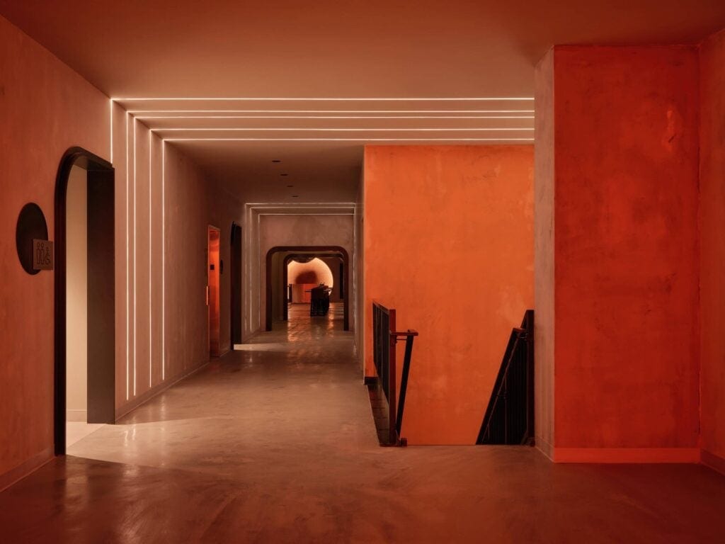 A corridor at HISTORY Ottawa lined with nested rectangular frames of light receding toward an arched opening, with a washroom sign on the left wall.